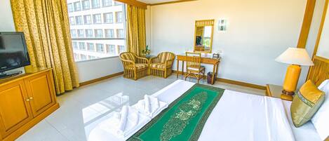 A hotel room with a bed, a desk, a chair, a television, and a window with curtains.