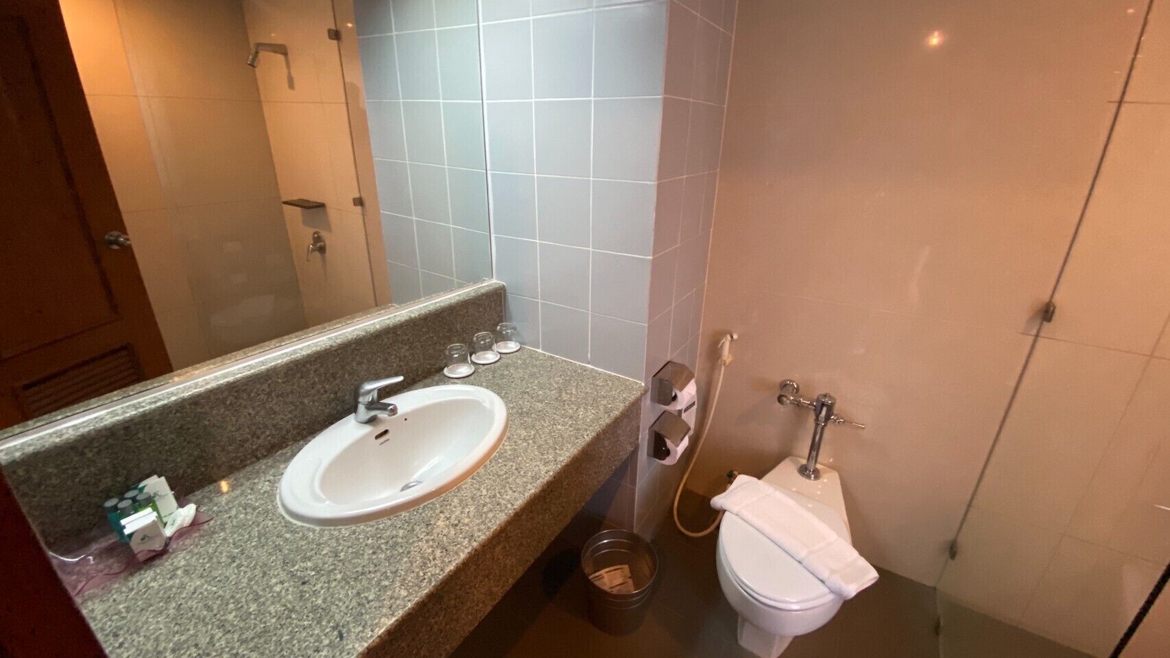 A bathroom with a granite countertop, a white sink, a mirror, a toilet, and a shower.