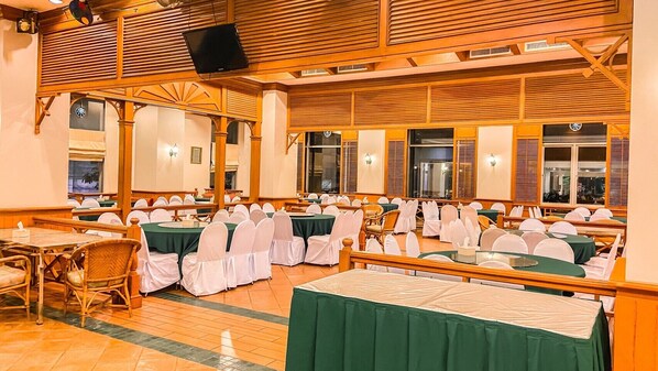 A banquet hall with rows of tables and chairs, wooden paneling on the ceiling, and large windows. - K Park Grand Hotel (Surat Thani)