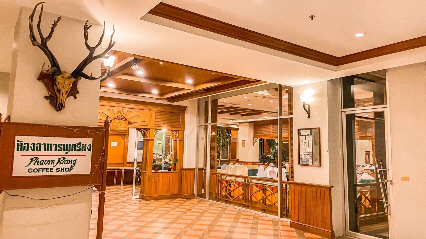 A coffee shop with a sign in a foreign language, wooden interior, and a tiled floor.