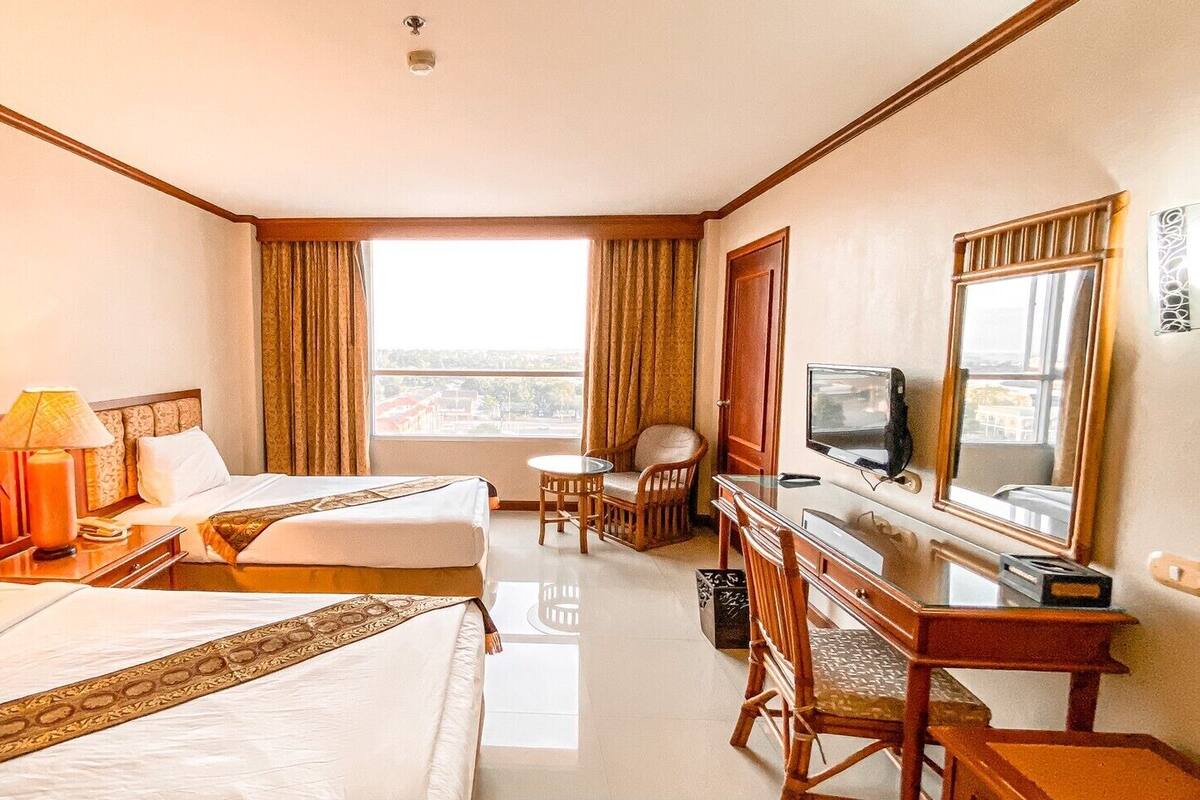 Une chambre d’hôtel avec deux lits, un bureau avec une télévision, une chaise et une vue sur la ville.