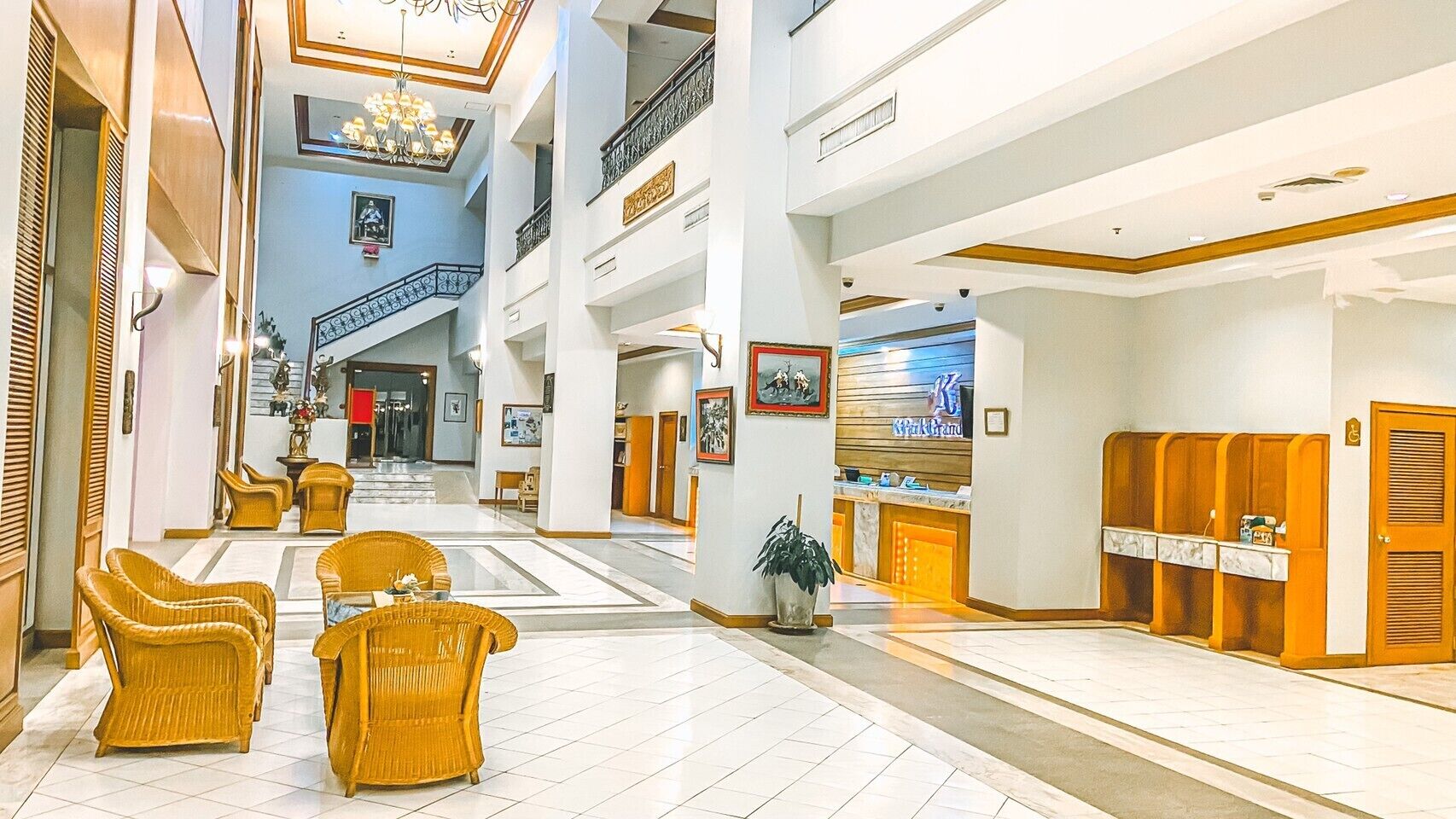 A spacious lobby with high ceilings, a central staircase, and a reception desk.
