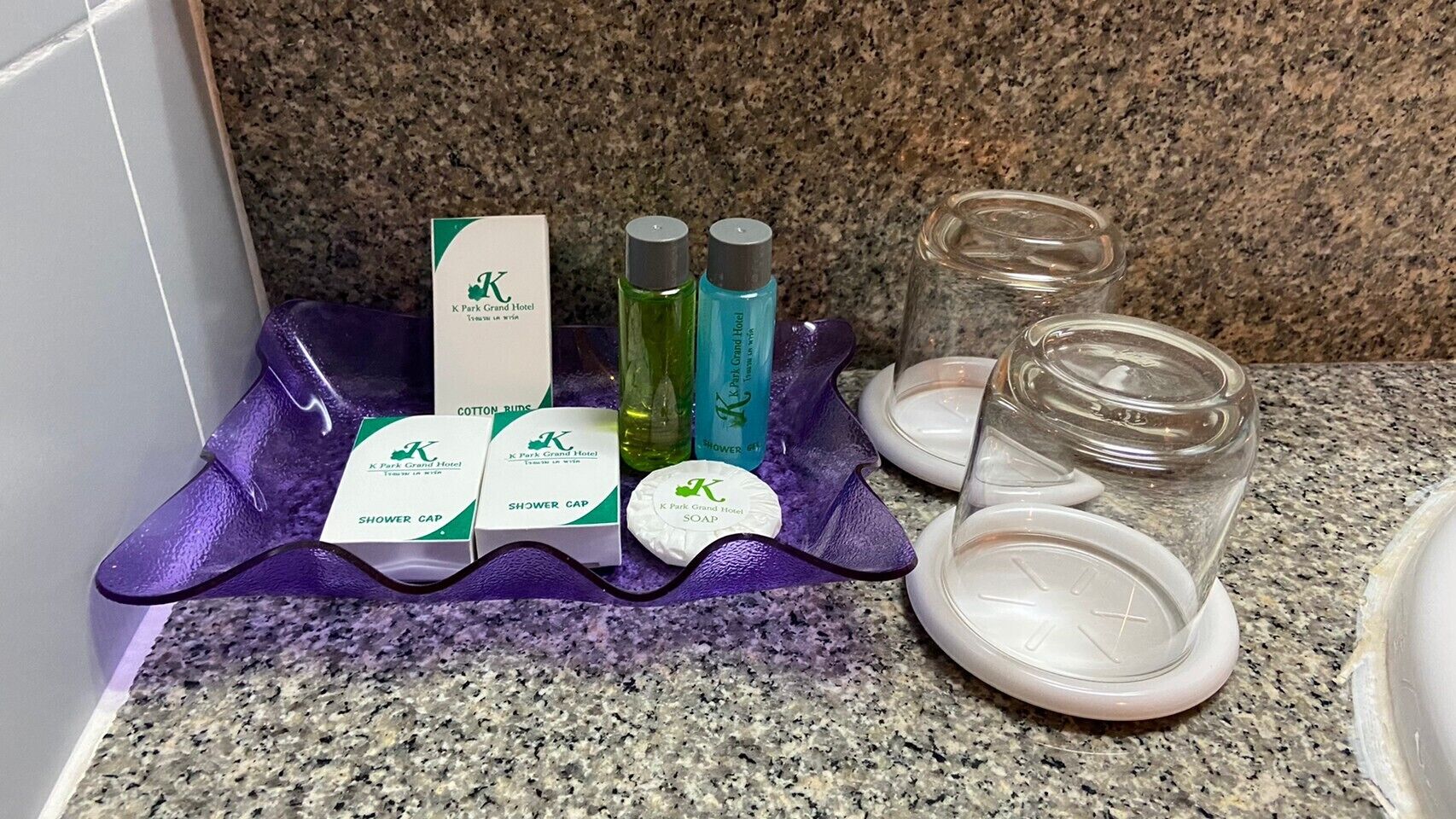 A bathroom counter with toiletries including shower caps, soap, and bottles of shampoo and conditioner.