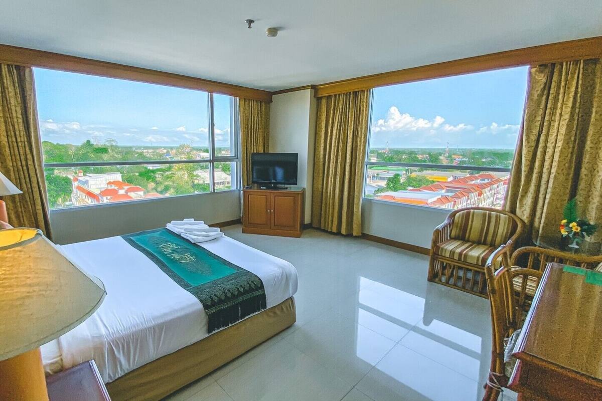 Une chambre d’hôtel avec un grand lit, une télévision, un canapé et une vue sur la ville.