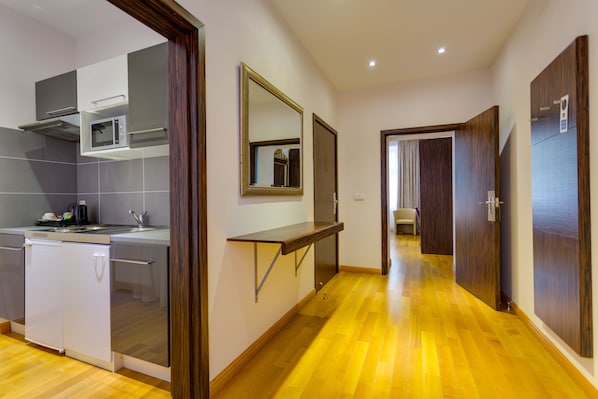 A modern kitchen with built-in appliances, a wooden floor, and a hallway leading to a bedroom. - Best Western Plus Hotel Arcadia (Vienna)