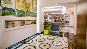 Un vestíbulo de hotel con una recepción, una gran obra de arte en la pared y un suelo estampado.
