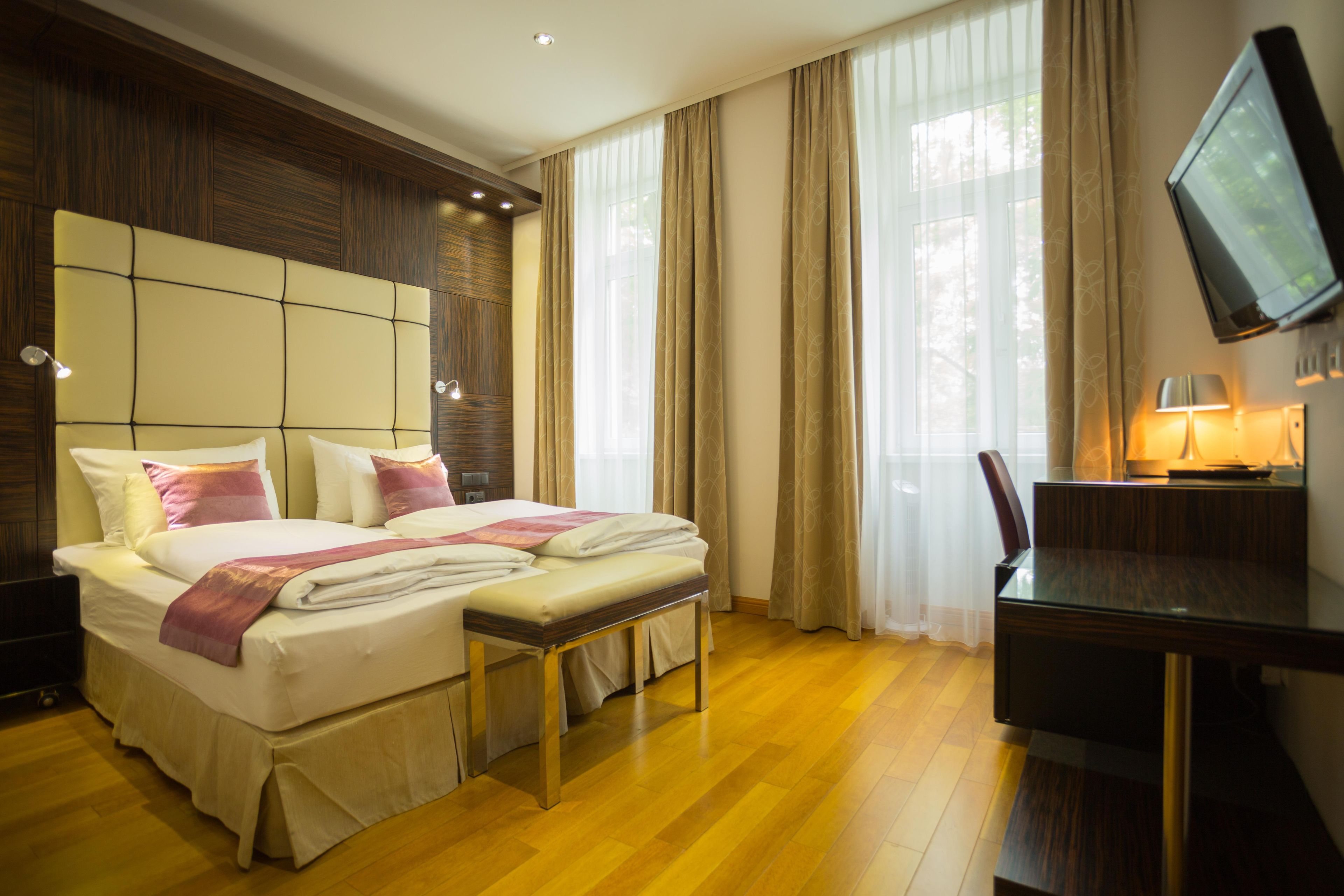 Habitación de hotel con cama, mesita de noche, escritorio, silla y televisión.