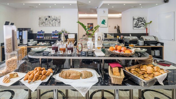 Zona de bufé con diferentes opciones de comida, incluyendo pasteles, pan y frutas.
