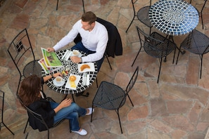 A couple dining at a round table with a mosaic top, surrounded by stone flooring and metal chairs. - Best Western Plus Hotel Arcadia (Vienna)
