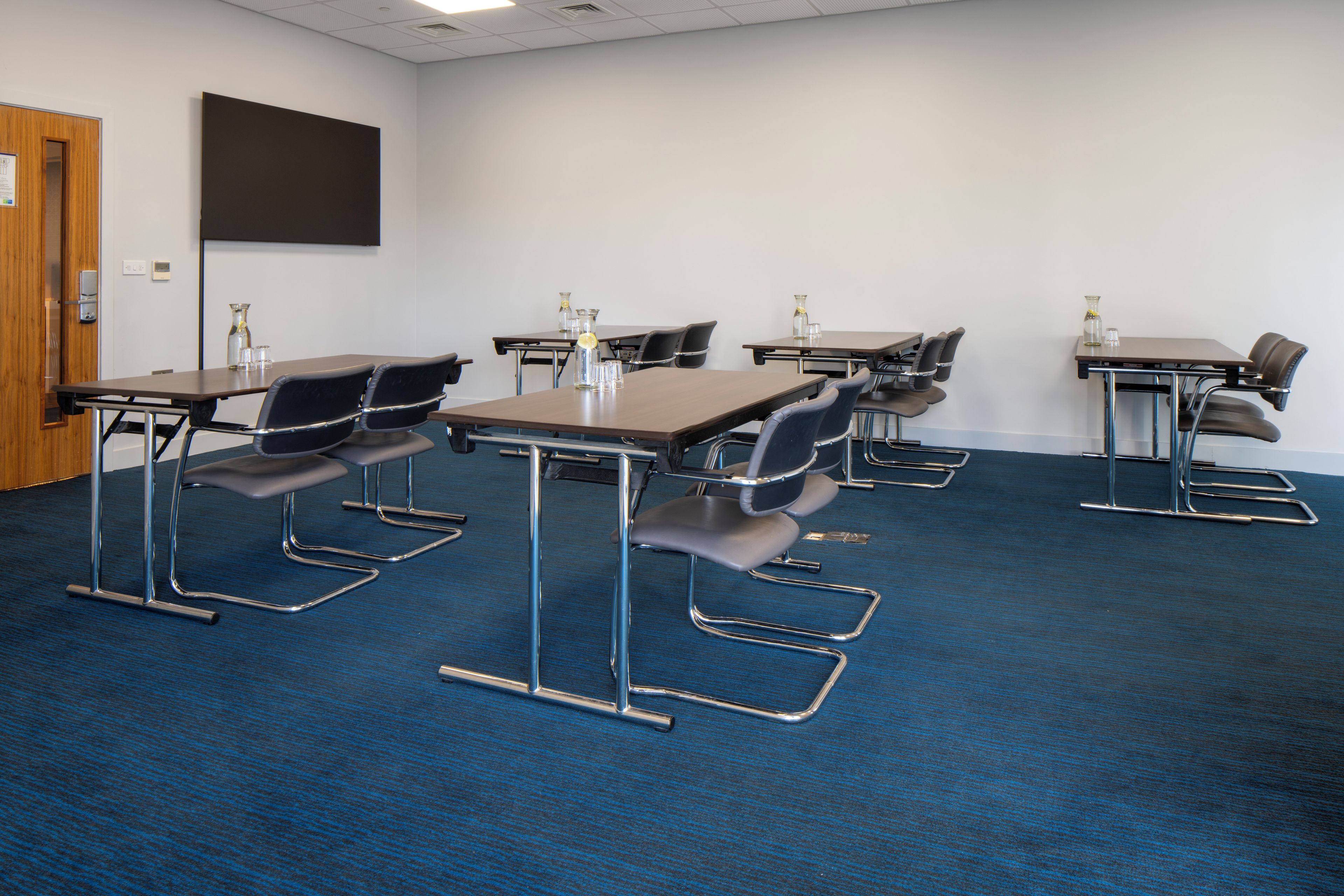 Une salle de conférence équipée de tables, de chaises et d’un écran de projection.