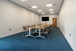 A conference room with a long table, chairs, a flat-screen TV, and a door. - Holiday Inn Express Birmingham - Snow Hill by IHG (Birmingham)