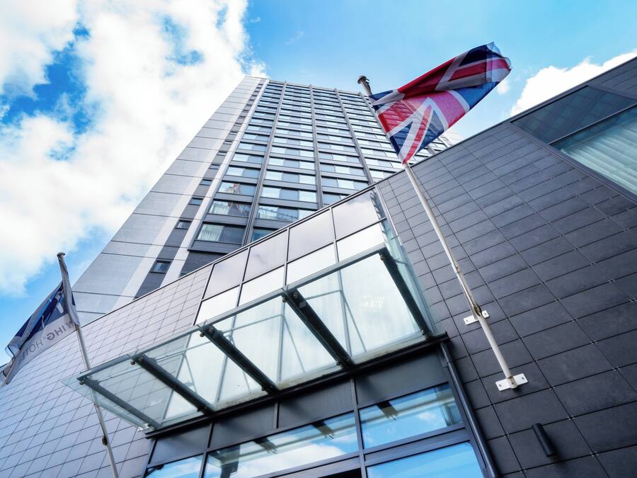 A modern building with a glass facade and a flagpole with a flag.