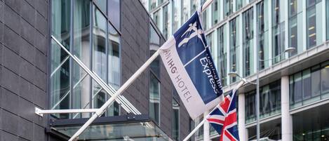 A flag with 'ANIING HOTEL' and 'Express' text, a British flag, and a modern building with large windows.