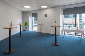 A room with four round tables, each with a bottle and glasses, and a potted plant. - Holiday Inn Express Birmingham - Snow Hill by IHG (Birmingham)