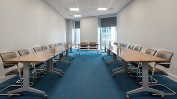 Une salle de conférence avec une longue table, des chaises et un sol recouvert de moquette.
