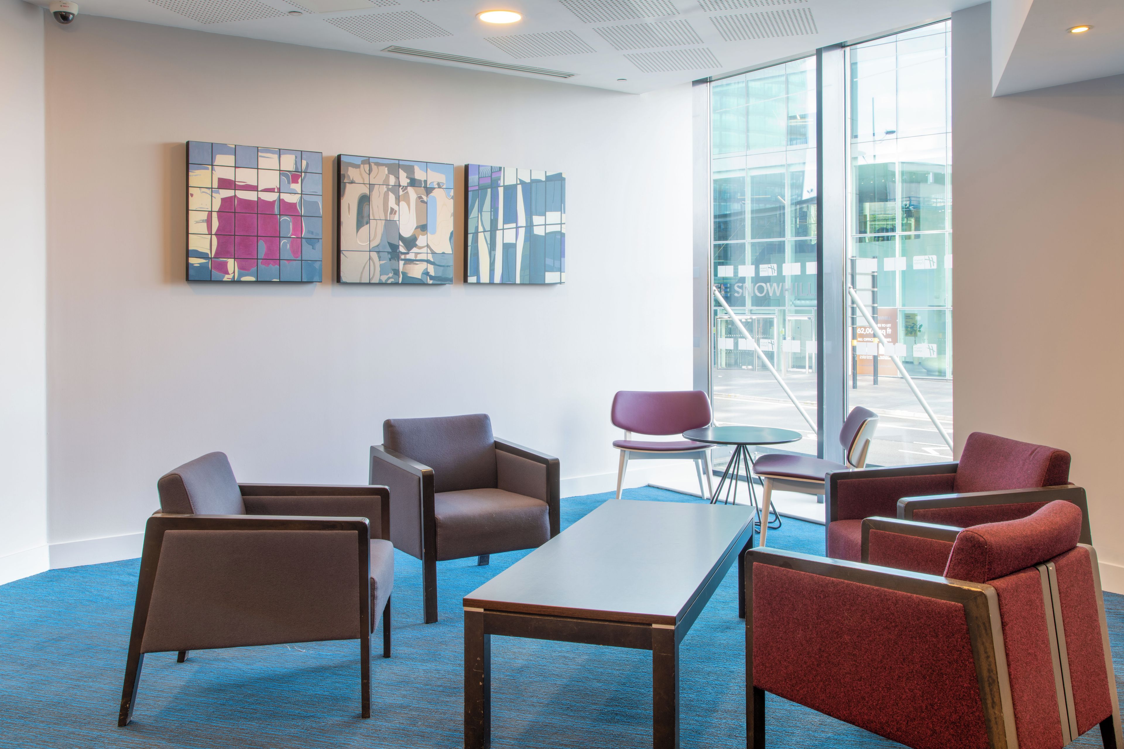 A modern interior with a blue carpet, a central table, and multiple chairs.