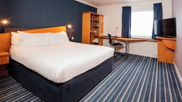A hotel room with a large bed, a desk, a chair, a television, and a wardrobe.