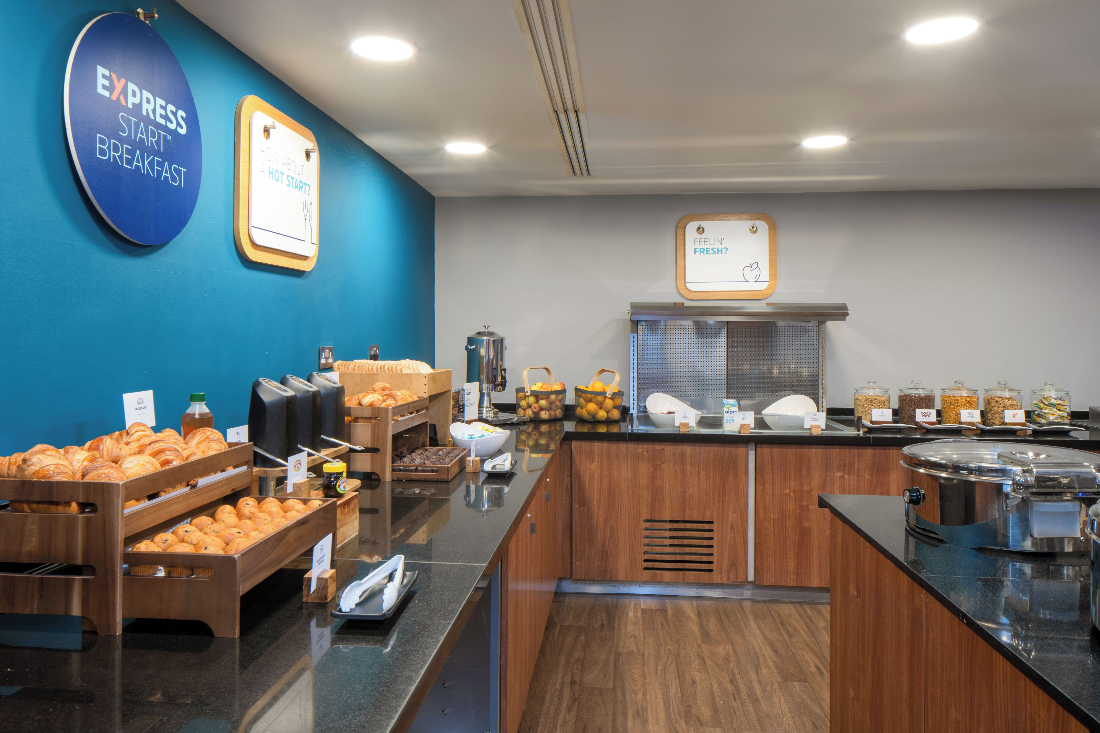 A breakfast buffet area with various food items and a coffee station.
