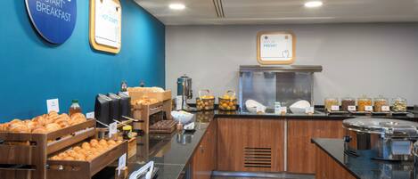 A breakfast buffet area with various food items and a coffee station.