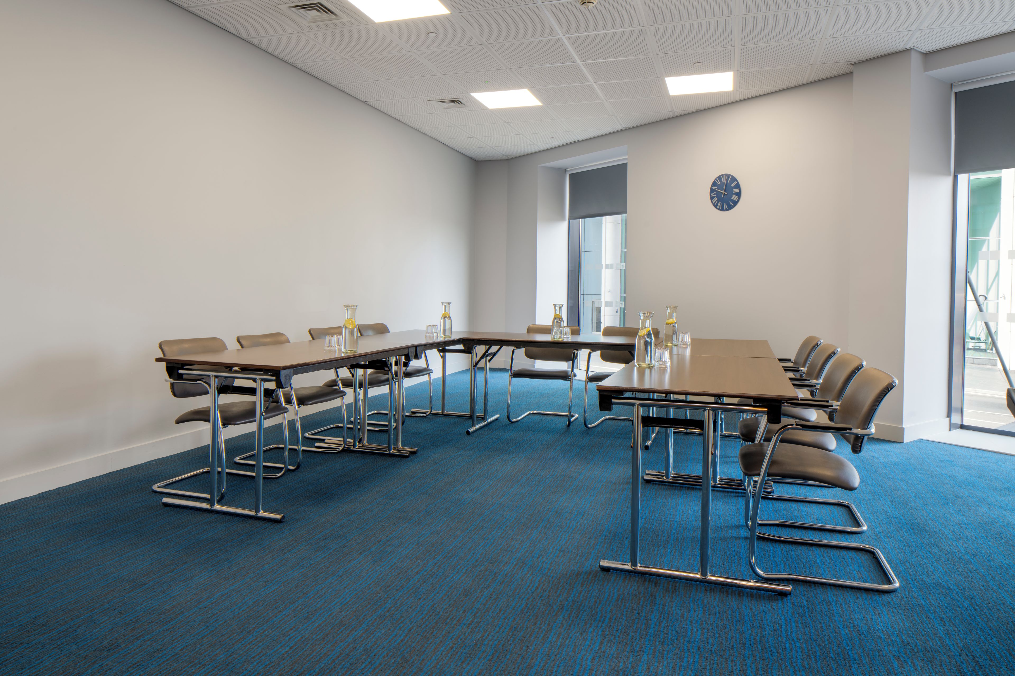 A conference room with a long table, chairs, and a clock on the wall.