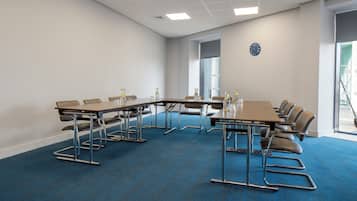 A conference room with a long table, chairs, and a clock on the wall.