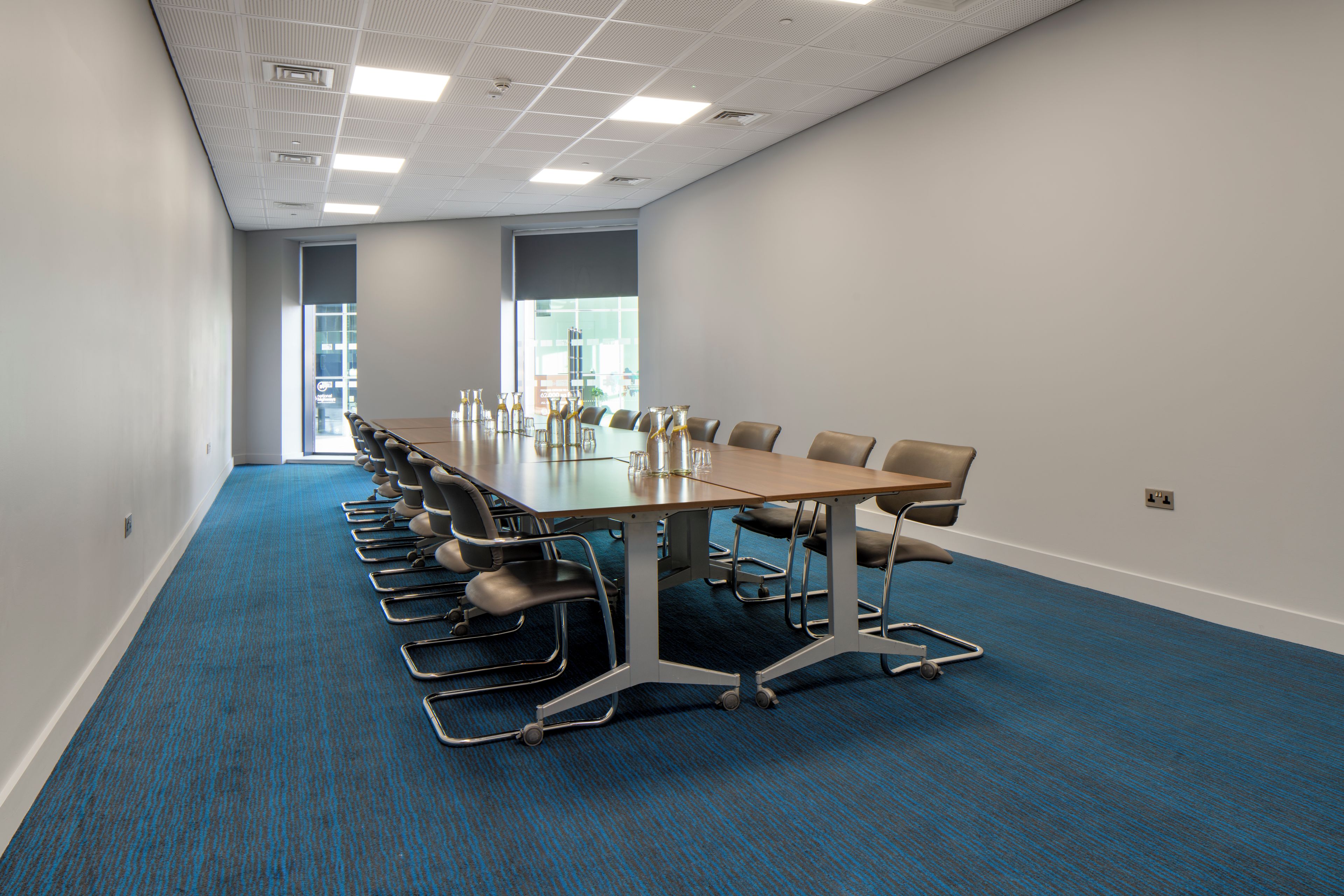 A conference room with a long table, chairs, and a carpeted floor.