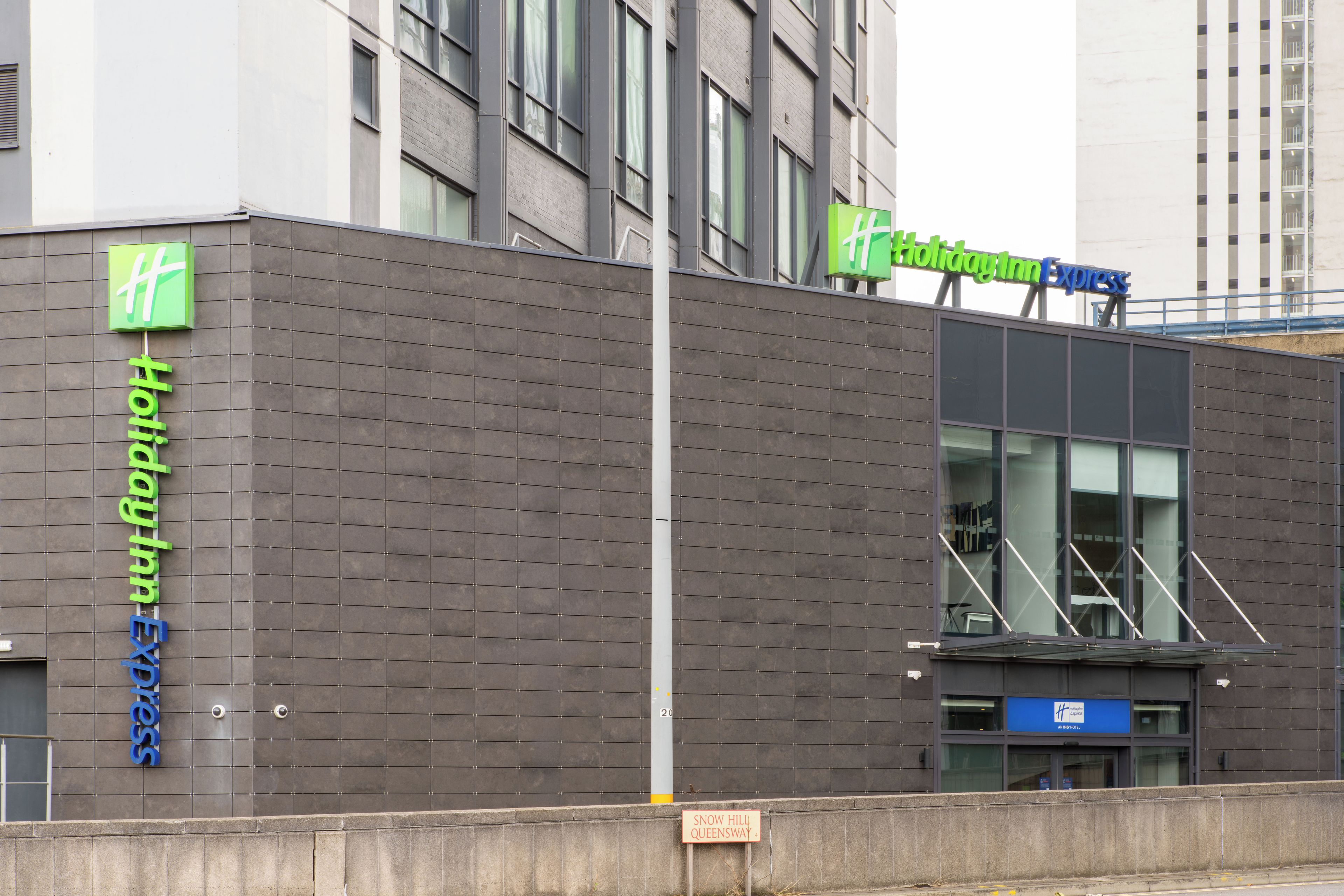 Un edificio moderno con il cartello Holiday Inn Express, il logo Holiday Inn Express e un segnale che indica 'Snow Hill Queensway 4'.