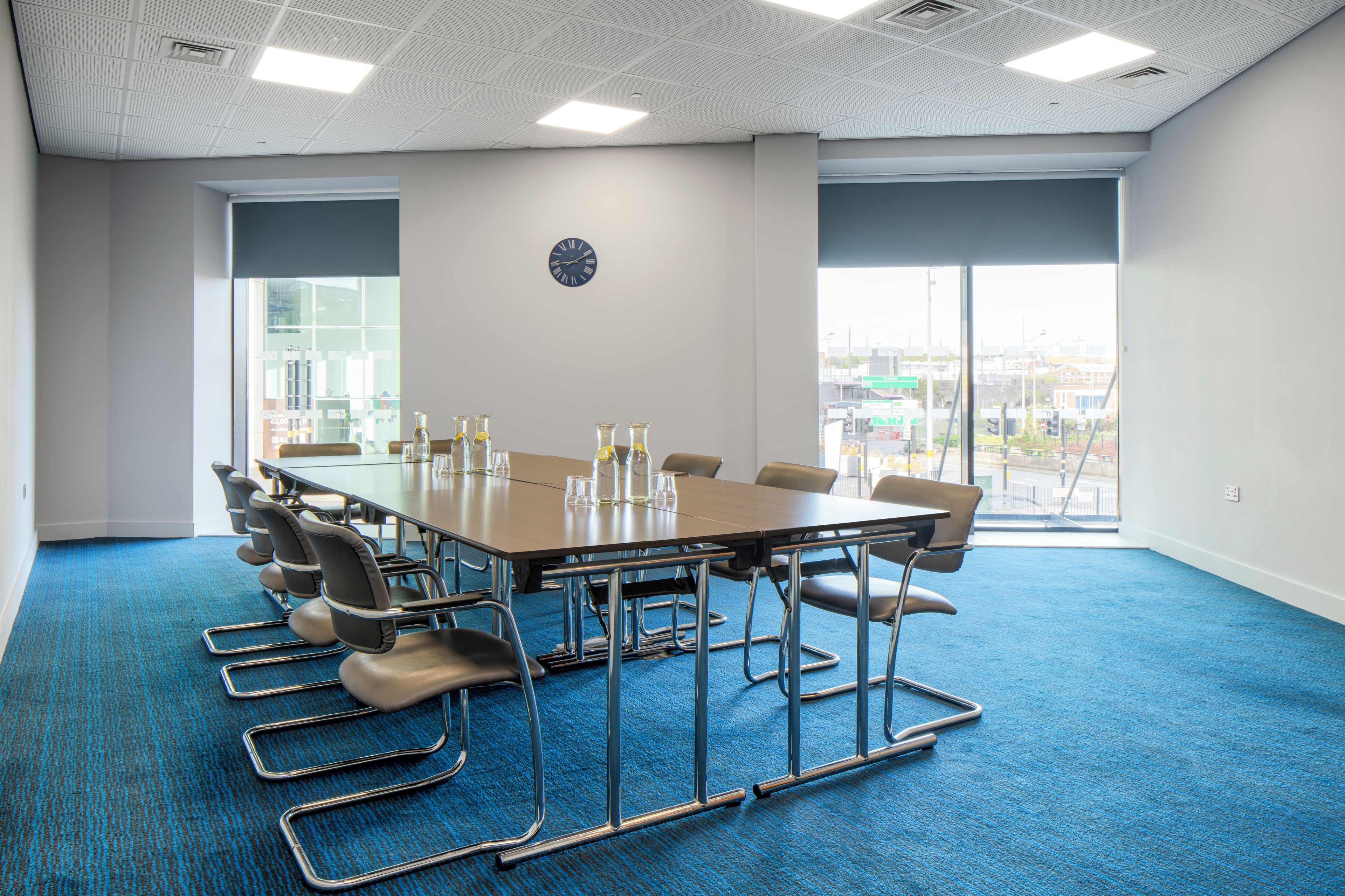 A conference room with a long table, chairs, and a clock on the wall.