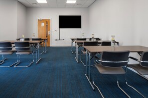 A conference room with a flat-screen TV, multiple tables, and chairs. - Holiday Inn Express Birmingham - Snow Hill by IHG (Birmingham)