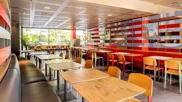 Interior de un restaurante moderno con cabinas y mesas, techo con diseño y vistas a zonas verdes.