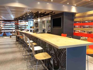 A modern bar area with a long counter, bar stools, and a bar refrigerator. - ibis Geneve Centre Nations (Geneva)