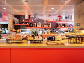 A breakfast buffet with various food items, a coffee machine, and decorative plants. - ibis Geneve Centre Nations (Geneva)