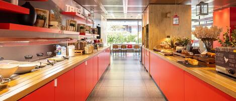 Una cocina moderna con armarios rojos, una encimera amplia con diversos alimentos y vistas al exterior.