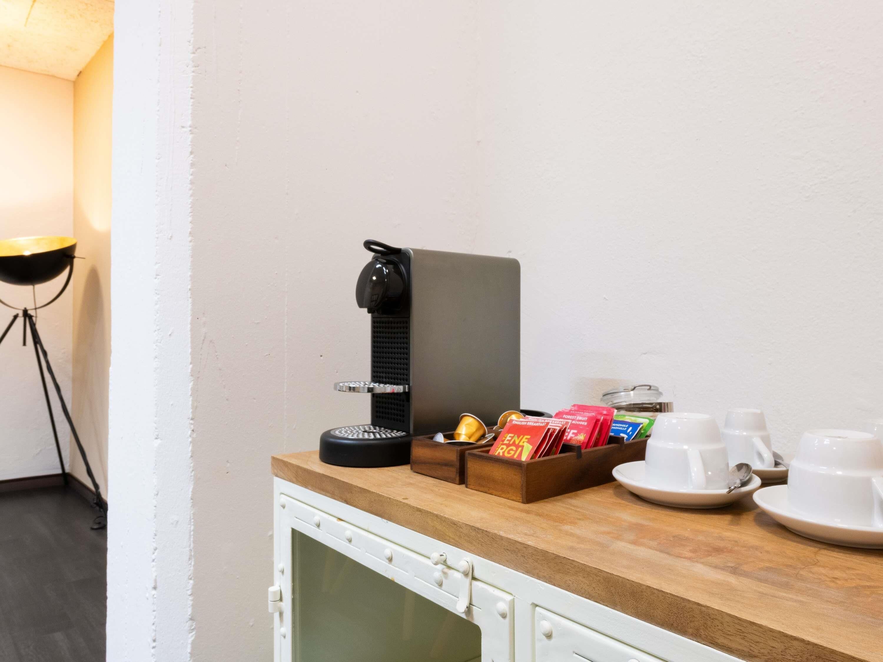 A kitchenette with a coffee machine, tea and coffee pods, and a small refrigerator.