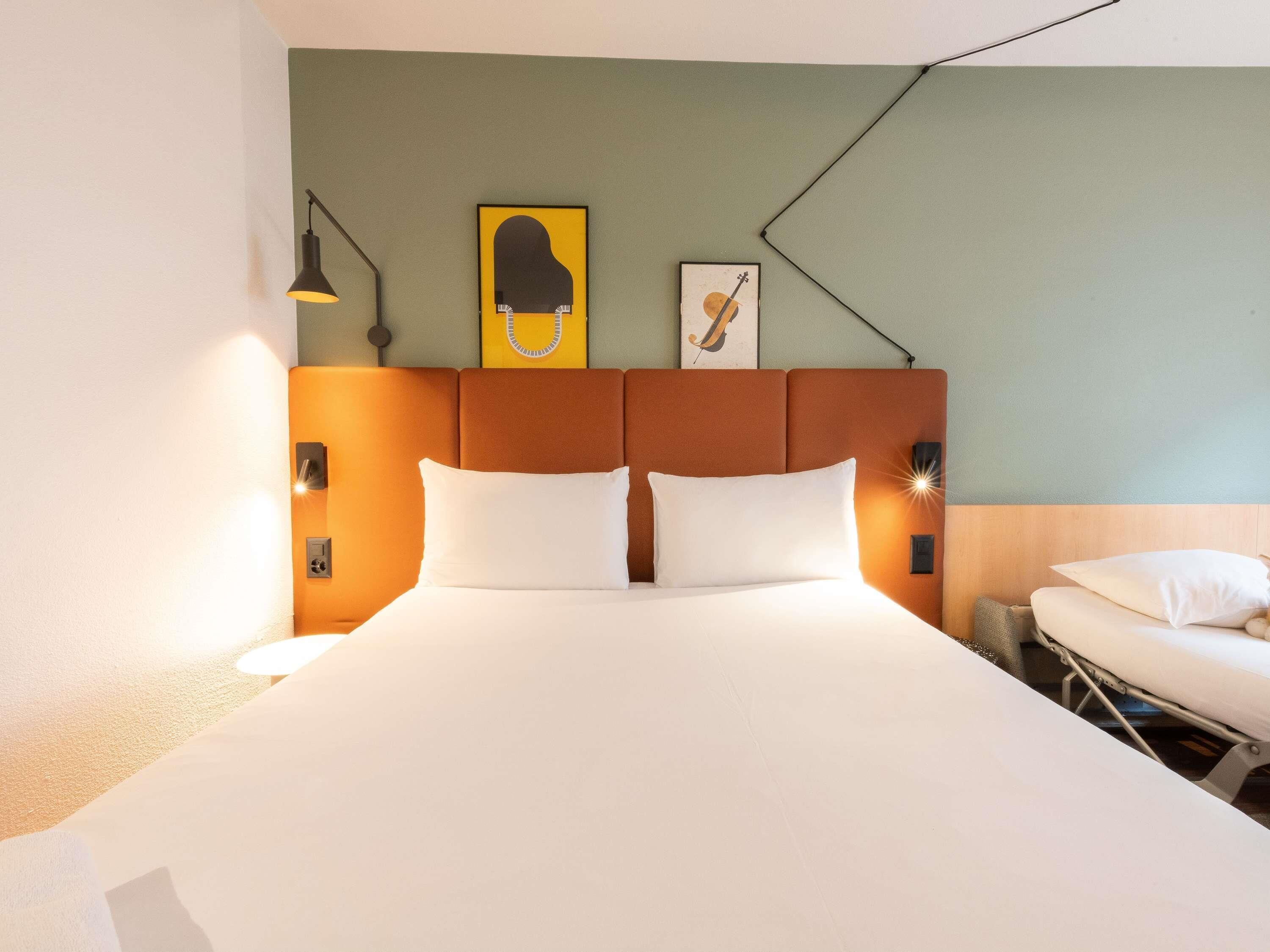 Una habitación de hotel con una cama grande, un cabecero de diseño único, una obra de arte en la pared y una mesita de noche con una lámpara.