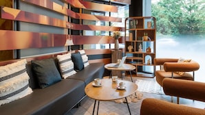 A modern interior with a sofa, a round table with a laptop, and a bookshelf. - ibis Geneve Centre Nations (Geneva)