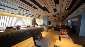 Un hall d’hôtel moderne comprenant un comptoir d’accueil, un espace salon et un bar.