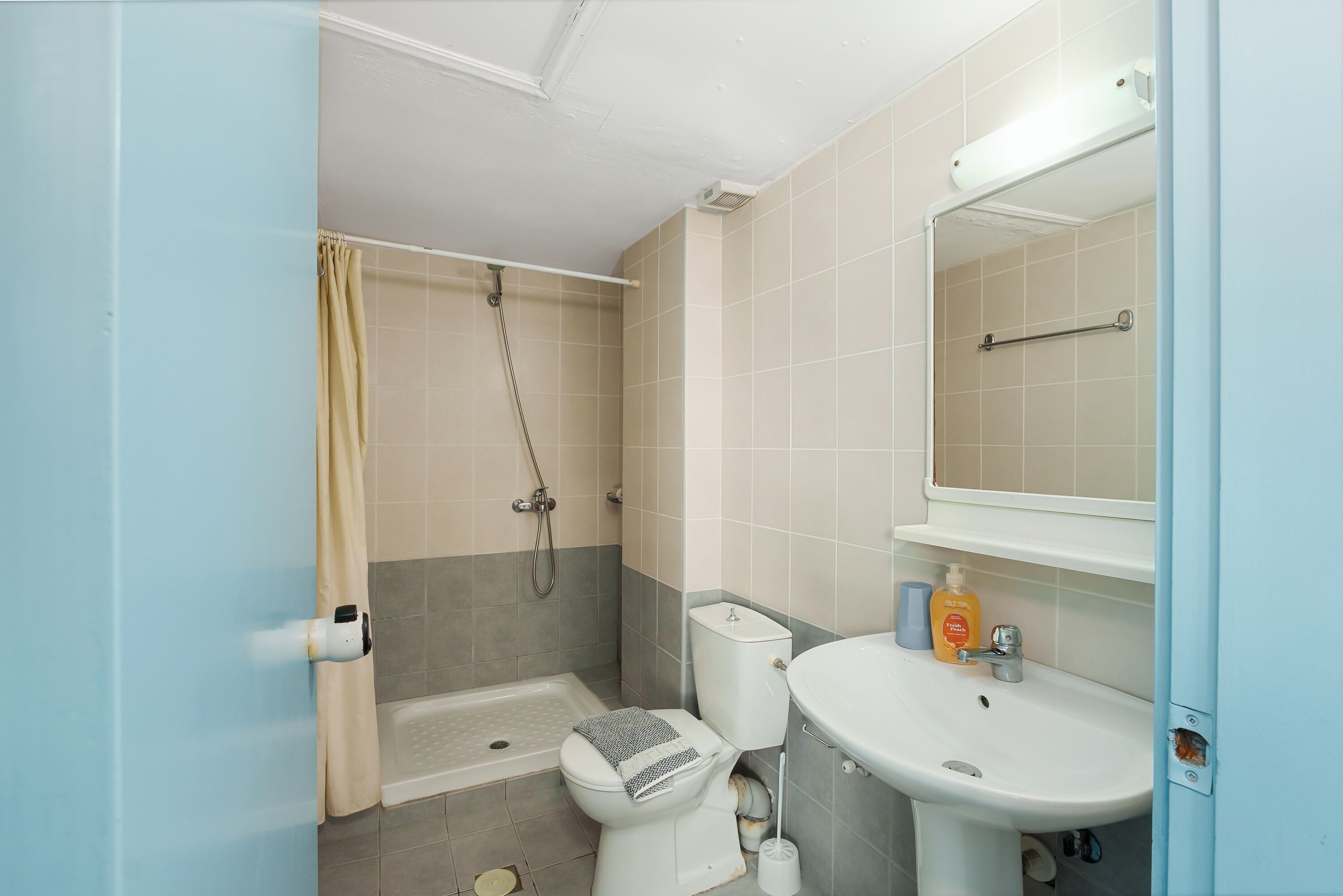 A bathroom with a shower, toilet, sink, and mirror.