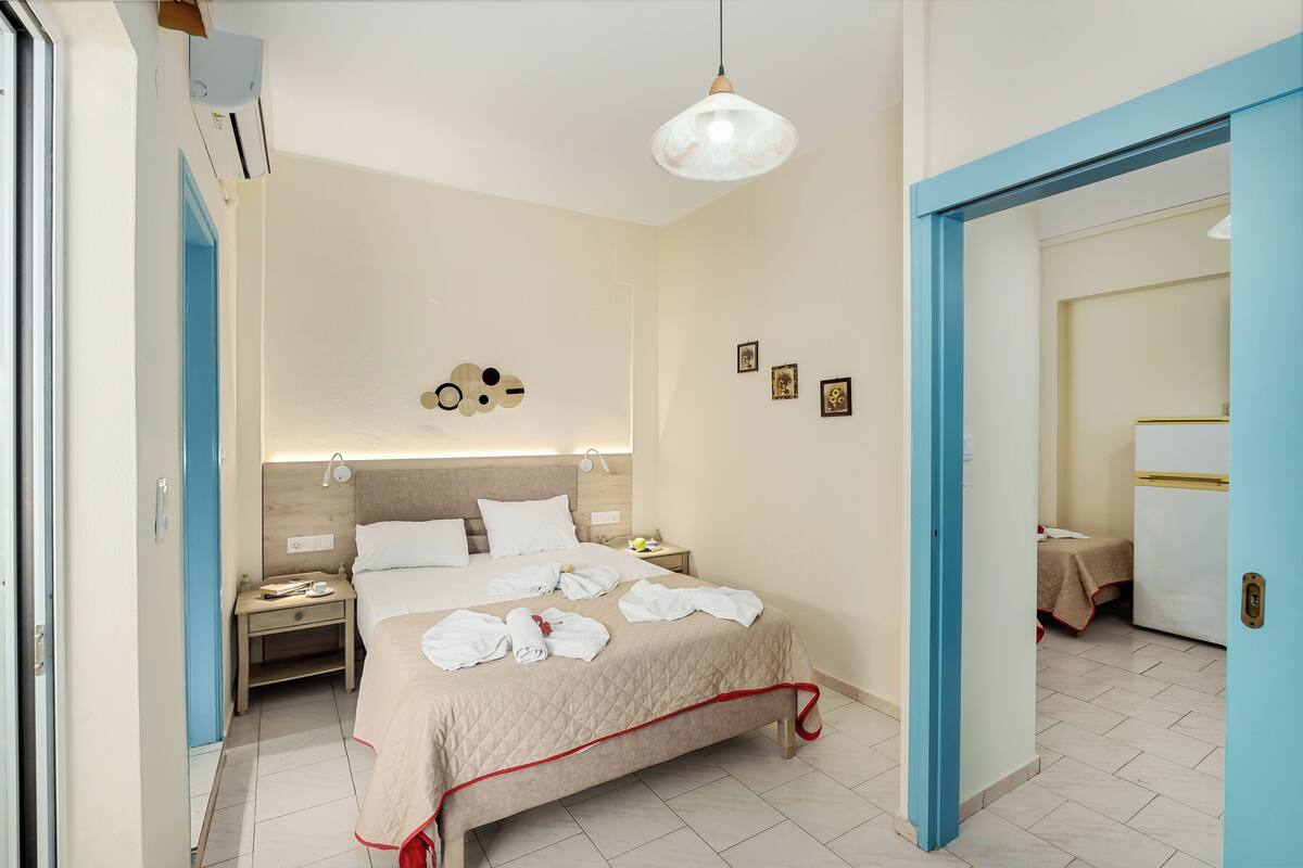 Une chambre d’hôtel avec un lit, des tables de chevet, une horloge murale et un luminaire au plafond.