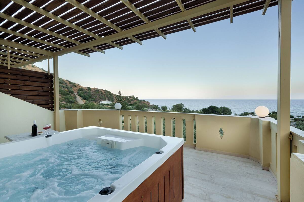 Un jacuzzi sur un balcon avec vue sur la mer et les collines.
