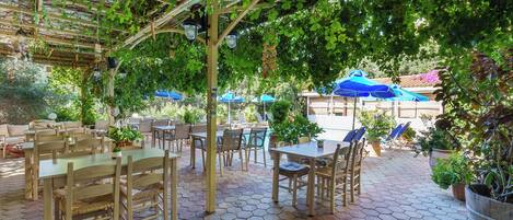 An outdoor patio area with hexagonal tiled flooring, wooden furniture, and potted plants.