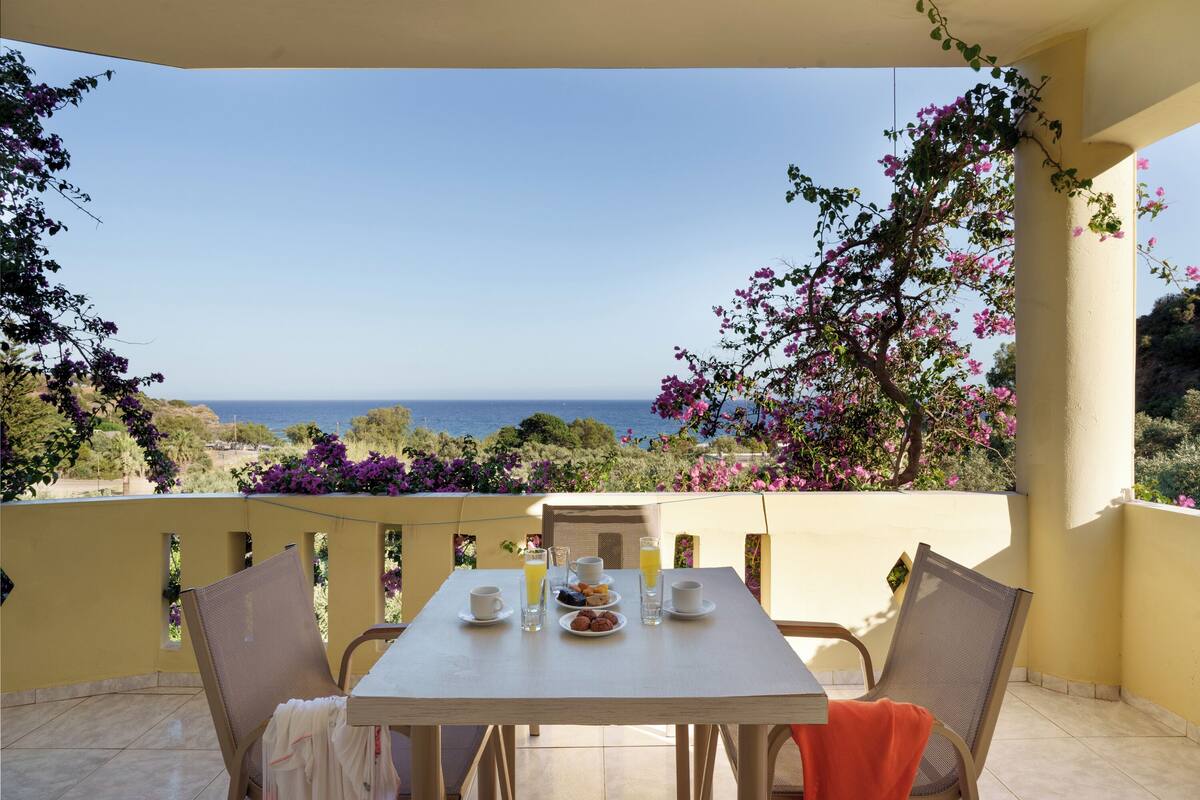 Un balcon avec une table préparée pour le petit-déjeuner, donnant sur la mer.