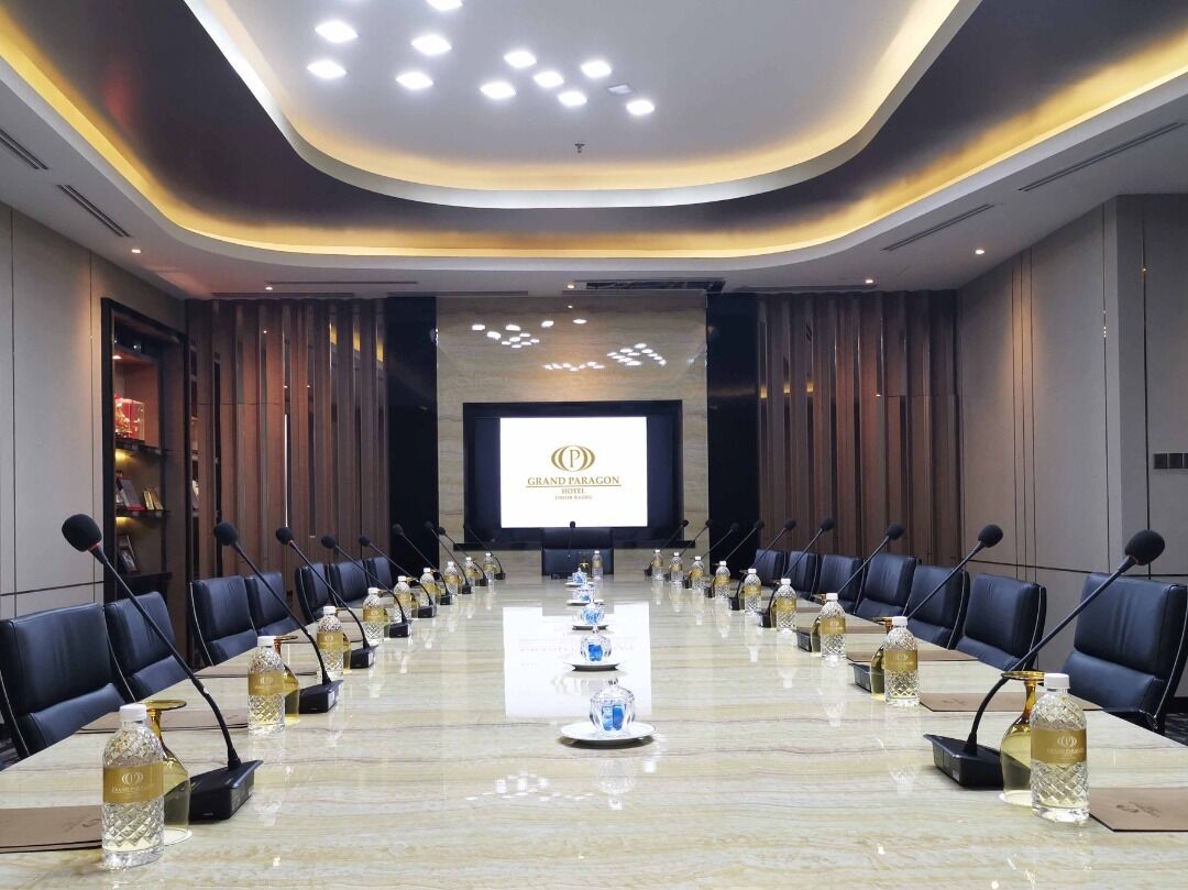 A conference room with a long table, microphones, and water bottles.