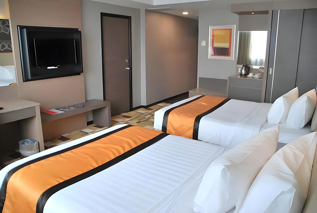A hotel room with two beds, a TV, a desk, and a bathroom.