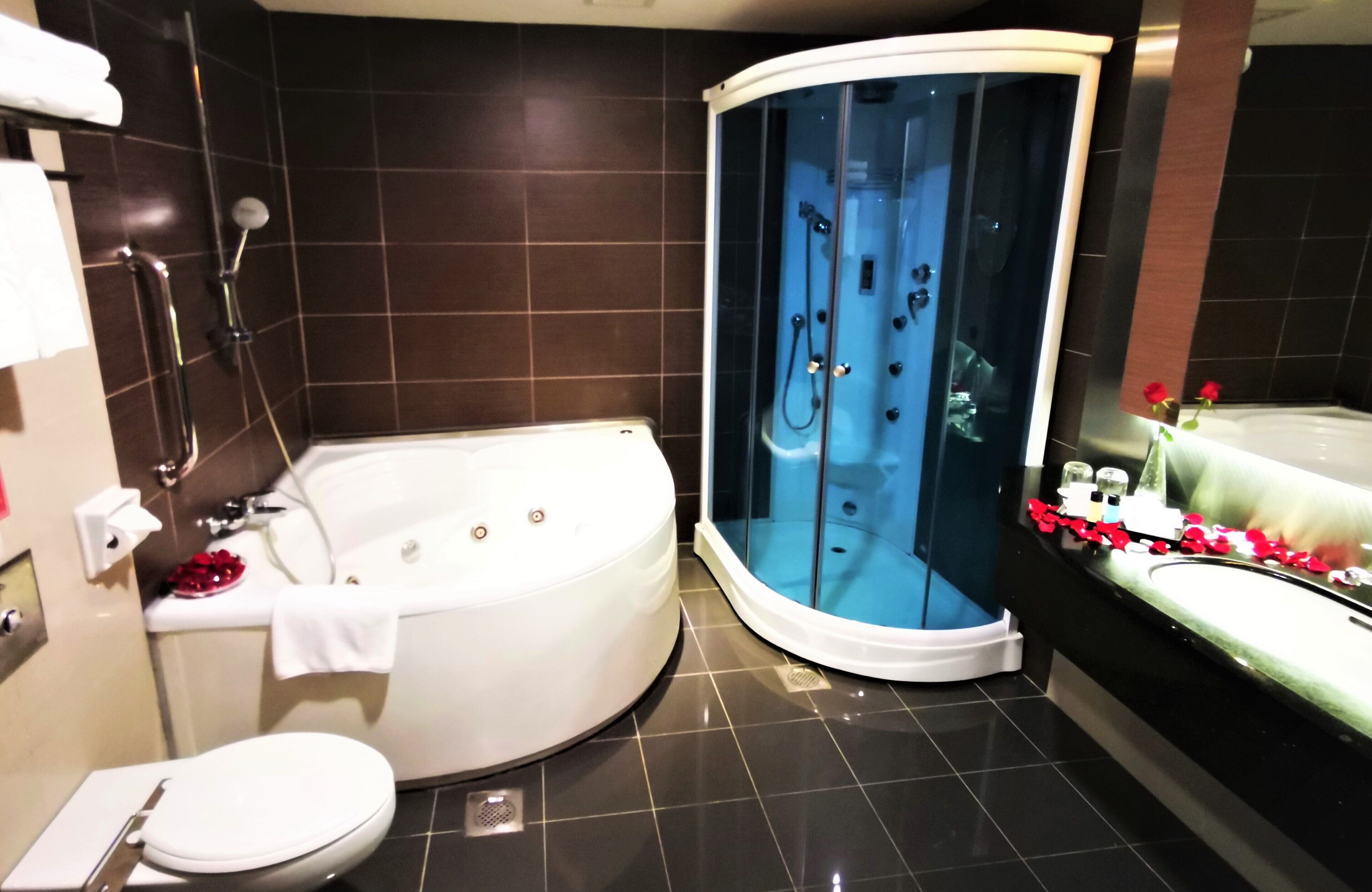 Un baño moderno con bañera, ducha y jacuzzi con mampara de vidrio.