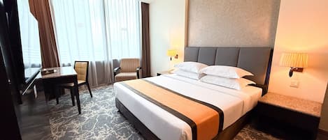 A hotel room with a large bed, a desk, a chair, and a view of the outdoors through the window.