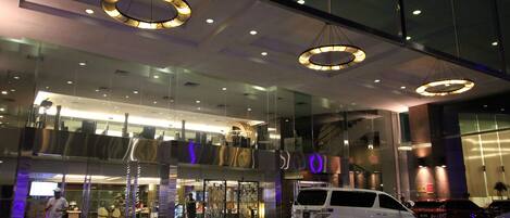 A modern building with a glass facade, large circular light fixtures, and a white van parked in front.