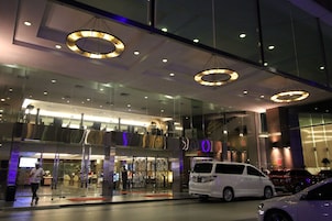 Um edifício moderno com fachada de vidro, grandes luminárias circulares e uma carrinha branca estacionada em frente.