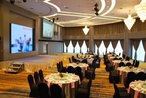 A banquet hall with round tables, chairs, and a stage.
