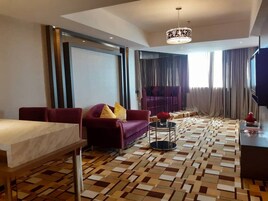 Un salon moderne avec un sol à motifs, un canapé avec des coussins, une petite table ronde et un téléviseur.
